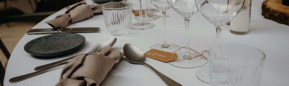 A sophisticated table setup featuring glasses, utensils, and napkins on a white tablecloth.