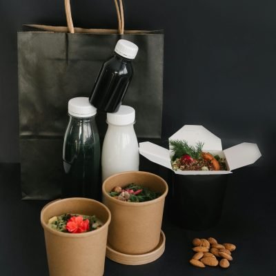 A collection of eco-friendly food containers and bottles on a black surface, highlighting sustainable takeaway options.